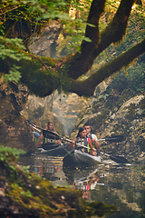 Image showing A group of friends enjoying having fun and kayaking while exploring the calm river, surrounding forest and large natural river canyons