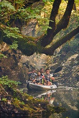 Image showing A group of friends enjoying having fun and kayaking while exploring the calm river, surrounding forest and large natural river canyons