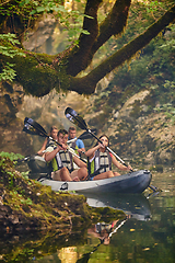 Image showing A group of friends enjoying having fun and kayaking while exploring the calm river, surrounding forest and large natural river canyons