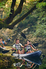 Image showing A group of friends enjoying having fun and kayaking while exploring the calm river, surrounding forest and large natural river canyons