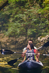 Image showing A young couple enjoying an idyllic kayak ride in the middle of a beautiful river surrounded by forest greenery