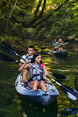 Image showing A group of friends enjoying having fun and kayaking while exploring the calm river, surrounding forest and large natural river canyons