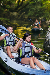 Image showing A group of friends enjoying having fun and kayaking while exploring the calm river, surrounding forest and large natural river canyons