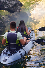 Image showing A young couple enjoying an idyllic kayak ride in the middle of a beautiful river surrounded by forest greenery