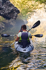 Image showing A young couple enjoying an idyllic kayak ride in the middle of a beautiful river surrounded by forest greenery
