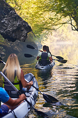 Image showing A group of friends enjoying having fun and kayaking while exploring the calm river, surrounding forest and large natural river canyons