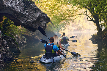 Image showing A group of friends enjoying having fun and kayaking while exploring the calm river, surrounding forest and large natural river canyons