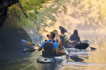 Image showing A group of friends enjoying having fun and kayaking while exploring the calm river, surrounding forest and large natural river canyons