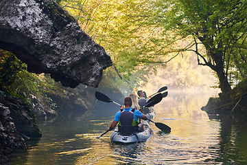 Image showing A group of friends enjoying having fun and kayaking while exploring the calm river, surrounding forest and large natural river canyons