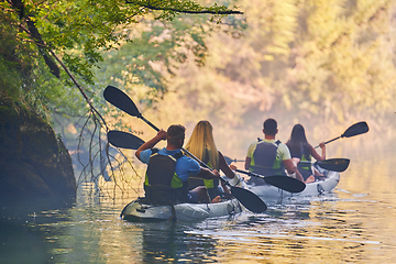 Image showing A group of friends enjoying having fun and kayaking while exploring the calm river, surrounding forest and large natural river canyons