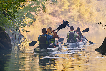 Image showing A group of friends enjoying having fun and kayaking while exploring the calm river, surrounding forest and large natural river canyons