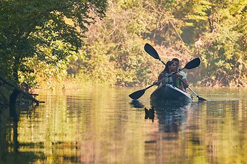 Image showing A group of friends enjoying having fun and kayaking while exploring the calm river, surrounding forest and large natural river canyons