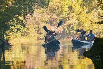 Image showing A group of friends enjoying having fun and kayaking while exploring the calm river, surrounding forest and large natural river canyons