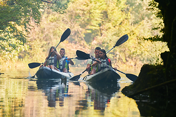 Image showing A group of friends enjoying having fun and kayaking while exploring the calm river, surrounding forest and large natural river canyons