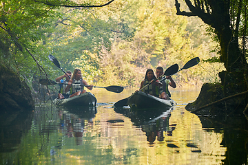 Image showing A group of friends enjoying having fun and kayaking while exploring the calm river, surrounding forest and large natural river canyons