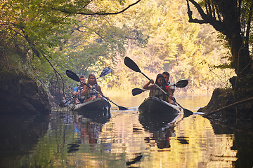 Image showing A group of friends enjoying having fun and kayaking while exploring the calm river, surrounding forest and large natural river canyons
