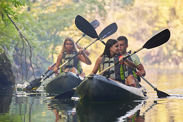 Image showing A group of friends enjoying having fun and kayaking while exploring the calm river, surrounding forest and large natural river canyons