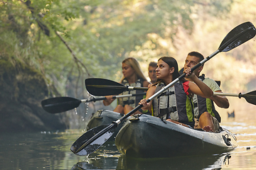 Image showing A group of friends enjoying having fun and kayaking while exploring the calm river, surrounding forest and large natural river canyons