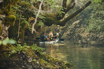 Image showing A group of friends enjoying having fun and kayaking while exploring the calm river, surrounding forest and large natural river canyons