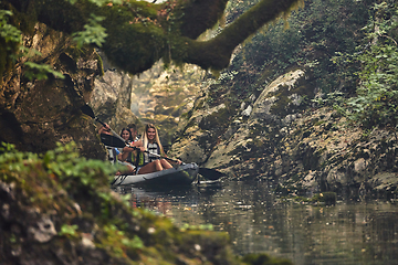 Image showing A group of friends enjoying having fun and kayaking while exploring the calm river, surrounding forest and large natural river canyons