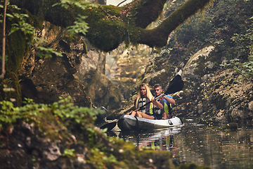 Image showing A group of friends enjoying having fun and kayaking while exploring the calm river, surrounding forest and large natural river canyons