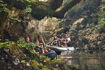 Image showing A group of friends enjoying having fun and kayaking while exploring the calm river, surrounding forest and large natural river canyons