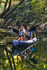 Image showing A group of friends enjoying having fun and kayaking while exploring the calm river, surrounding forest and large natural river canyons