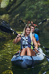 Image showing A group of friends enjoying having fun and kayaking while exploring the calm river, surrounding forest and large natural river canyons