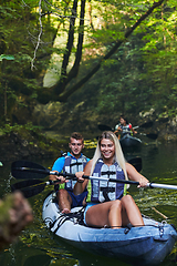 Image showing A group of friends enjoying having fun and kayaking while exploring the calm river, surrounding forest and large natural river canyons