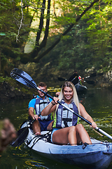 Image showing A group of friends enjoying having fun and kayaking while exploring the calm river, surrounding forest and large natural river canyons