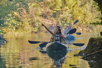 Image showing A group of friends enjoying having fun and kayaking while exploring the calm river, surrounding forest and large natural river canyons