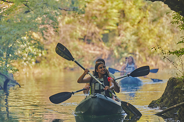 Image showing A group of friends enjoying having fun and kayaking while exploring the calm river, surrounding forest and large natural river canyons