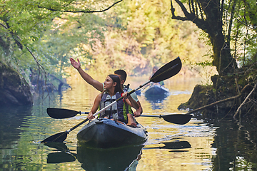 Image showing A group of friends enjoying having fun and kayaking while exploring the calm river, surrounding forest and large natural river canyons