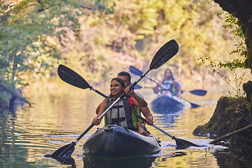 Image showing A group of friends enjoying having fun and kayaking while exploring the calm river, surrounding forest and large natural river canyons