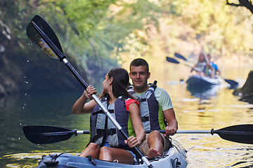 Image showing A group of friends enjoying having fun and kayaking while exploring the calm river, surrounding forest and large natural river canyons