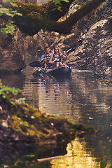 Image showing A young couple enjoying an idyllic kayak ride in the middle of a beautiful river surrounded by forest greenery