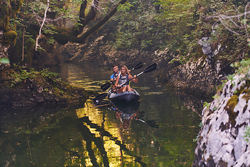 Image showing A young couple enjoying an idyllic kayak ride in the middle of a beautiful river surrounded by forest greenery