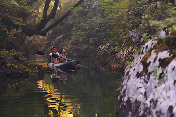 Image showing A young couple enjoying an idyllic kayak ride in the middle of a beautiful river surrounded by forest greenery