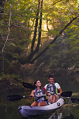 Image showing A young couple enjoying an idyllic kayak ride in the middle of a beautiful river surrounded by forest greenery