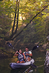 Image showing A young couple enjoying an idyllic kayak ride in the middle of a beautiful river surrounded by forest greenery