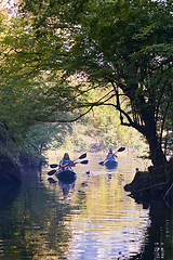 Image showing A group of friends enjoying having fun and kayaking while exploring the calm river, surrounding forest and large natural river canyons