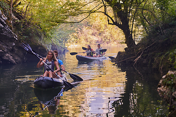 Image showing A group of friends enjoying having fun and kayaking while exploring the calm river, surrounding forest and large natural river canyons