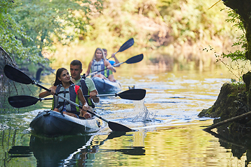 Image showing A group of friends enjoying having fun and kayaking while exploring the calm river, surrounding forest and large natural river canyons