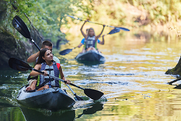 Image showing A group of friends enjoying having fun and kayaking while exploring the calm river, surrounding forest and large natural river canyons