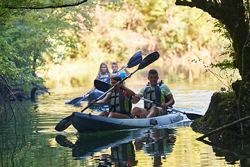 Image showing A group of friends enjoying having fun and kayaking while exploring the calm river, surrounding forest and large natural river canyons