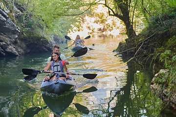 Image showing A group of friends enjoying having fun and kayaking while exploring the calm river, surrounding forest and large natural river canyons