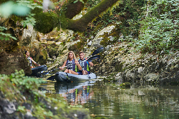 Image showing A young couple enjoying an idyllic kayak ride in the middle of a beautiful river surrounded by forest greenery