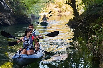 Image showing A group of friends enjoying having fun and kayaking while exploring the calm river, surrounding forest and large natural river canyons