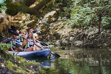 Image showing A group of friends enjoying having fun and kayaking while exploring the calm river, surrounding forest and large natural river canyons