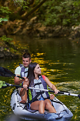 Image showing A young couple enjoying an idyllic kayak ride in the middle of a beautiful river surrounded by forest greenery